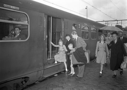 803553 Afbeelding van een vader met zijn twee kinderen tijdens het overstappen in een trein op het N.S.-station ...